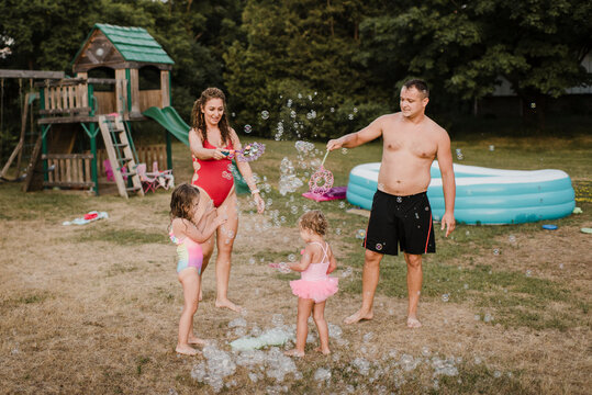 Happy family playing with soap bubbles in garden