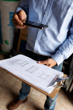 Architect taking smartphone picture of construction plan