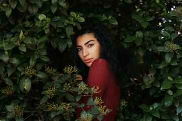Portrait of young black-haired woman between leaves