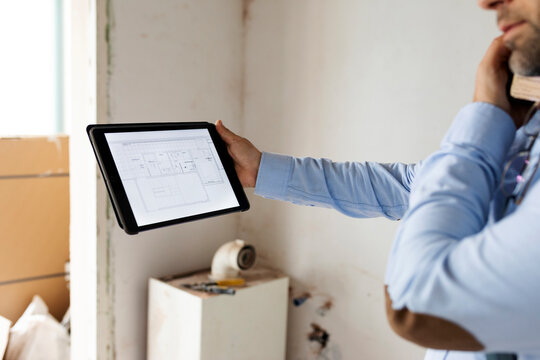 Architect holding tablet with construction plan