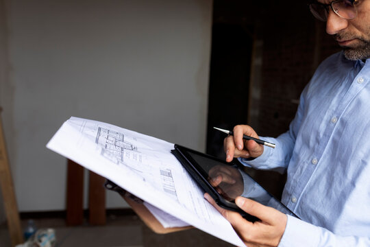 Architect at work with tablet and construction plan
