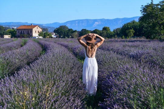 Woman wearing white dress and hat standing amidst lavender field