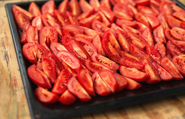  Tomatoes cut into wedges on a black pan. Tomato dishes. Tomato background.
