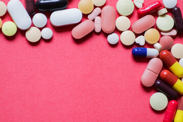 heap of tablets and capsules in pink background with space for text