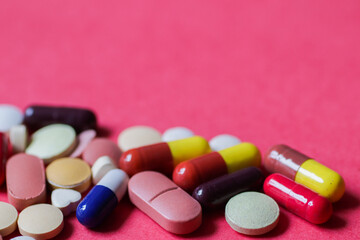 heap of tablets and capsules in pink background with space for text