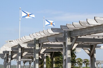 Two Nova Scotia flags blowing in the wind over an arbour
