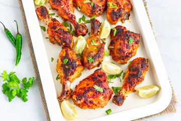 Spicy BBQ Grilled Chicken on a Baking Sheet Garnished with Cilantro, Green Chili Pepper and Lemon