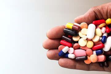 pile of medicine pills tablets capsules in a palm in white background