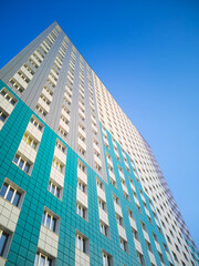 Obraz premium Green-beige multi-storey residential building, bottom view. Housing construction concept.