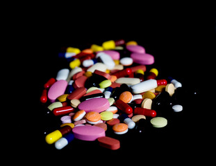 pile of medicine pills tablets capsules in black background