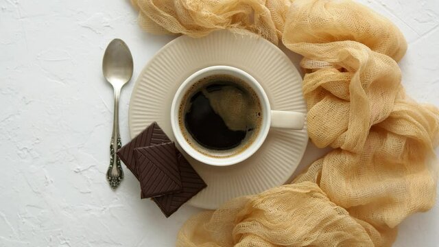 Black Coffee cup with dark chocolate on side. Placed on white kitchen table