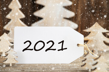 Obraz na płótnie Canvas Label With Text 2021. White Wooden Christmas Tree As Decoration. Brown Wooden Background With Snow