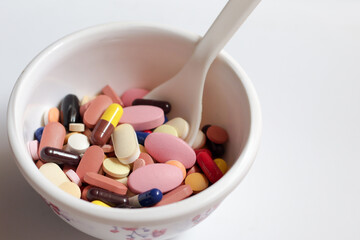 bowl of medicine pills tablets capsules in white background
