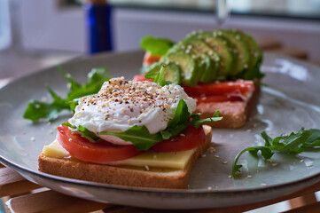 Healthy and beautiful breakfast of boiled eggs benedict, fresh vegetables of avocado, tomatoes and figs, watermelon on toast with black and strong coffee.