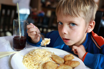 Child eating nuggets with spaghetti
