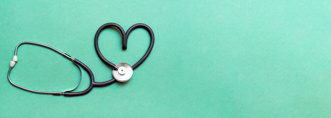 Stethoscope in Shape of Heart Isolated On Green Background. Banner. Copy space. Place for text.