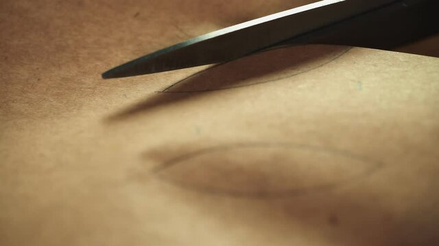 Close up of scissors cutting kraft paper with picture on it