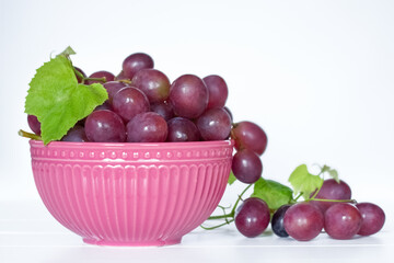 a bunch of grapes in a pink bowl on a white background close-up. background with pink grapes.