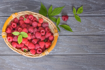 ripe raspberries in a wicker basket on a wooden background top view. background with raspberries. copy of the space. the raspberries lay flat on the table.