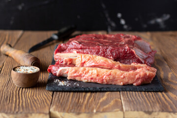 Raw beef fillet on slate board,  spicy salt on wooden boards. Food preparation