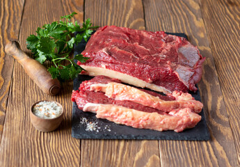 Raw beef fillet on slate board, fresh parsley and spicy salt. Food preparation