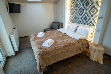 Interior of a spacious hotel bedroom with fresh linen on a big double bed. Cozy contemporary room in a modern house.