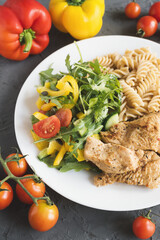 Baked turkey breast pieces, fresh salad with vegetables and whole wheat fusilli pasta. Healthy eating concept
