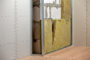 Wall of a room under renovation with mineral rock wool insulation and metal frame prepared for...