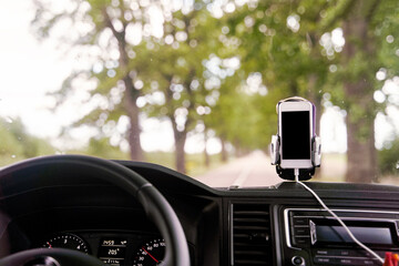 Mobile phone with GPS card in the car. A white smartphone on a stand in the car is used for navigation. High-quality photo