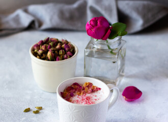 Fototapeta na wymiar Pink moon milk with almond milk, rose petals and cardamom, fresh flower and dried buds. Healthy nondairy vegan drink