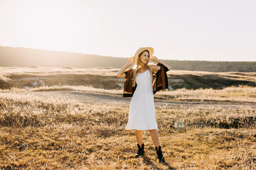 Young cheerful blonde woman in a field with dry grass.