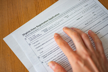 Naklejka premium Virginia Voter Registration Application form and female hand.