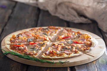 cutting board with hot testy pizza and bottle with oil and scapula on wooden background,close view 