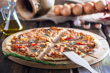cutting board with hot testy pizza and bottle with oil and scapula on wooden background,close view 