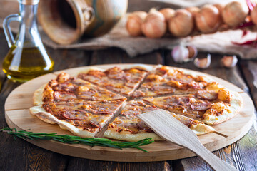 cutting board with hot testy pizza and bottle with oil and scapula on wooden background,close view 