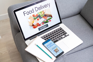 ordering food online concept: woman with a laptop showing fast food website on screen. Screen graphics are made up.