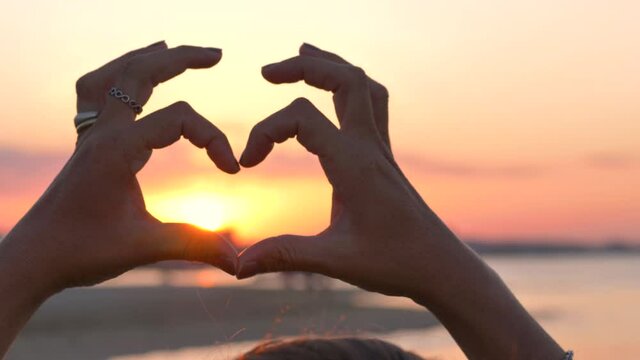the Silhouette hands making a heart shape ay sunset