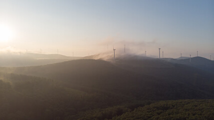 Eco wind park on the mountain. Aerial view of the sunrise with dawn and change global warming. Sustainable power with turbine for alternative energy and electricity. Environment and clean generator