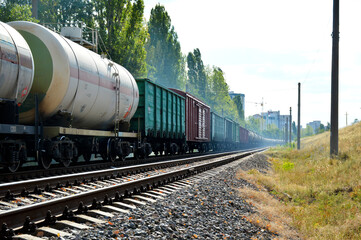 Fototapeta na wymiar a long line of freight cars going around the corner. in the foreground are tank wagons, then wagons for bulk and dry cargo