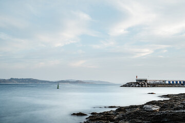 Rocks and small lighthouse on a calm foggy evening in the Rias Baixas in Galicia, Spain. Long exposure.