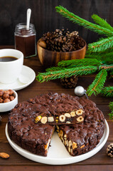 Panforte. Traditional Italian Christmas dessert with nuts and dried fruit on a white plate on a dark wooden background. Vertical, copy space.
