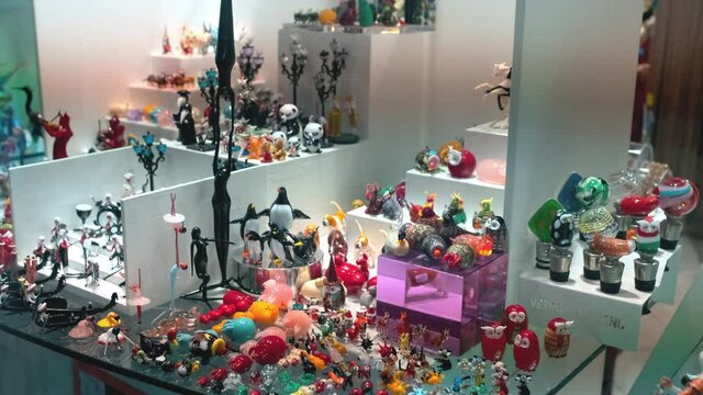 Indoor shoot of a souveniers, figurines and accessories on a stand. Lots of different glass-made souveniers placed on a stand with lit background.
