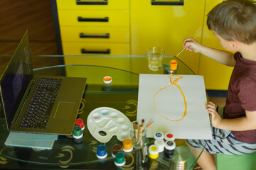 Beautiful creative boy is creativity and the artist in an online drawing paints lesson. Childrens creativity. The concept of distance learning online school for the period of war in Ukraine © Iryna
