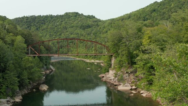 Steady flight of drone in aerial view towards 1912 historic metal truss Jenkinsburg Bridge near Mt Nebo and Morgantown over Cheat River