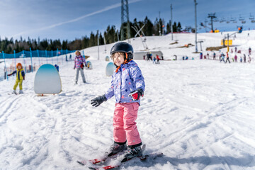 Young happy skier girl learning how to ski on the green ski zone. Young skier having fun on ski slope, Bialka Tatrzanska, Tatry, Poland