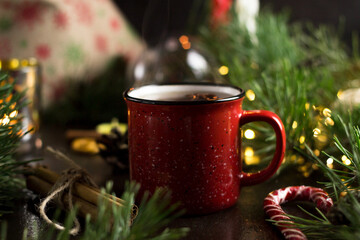 New year's tea party with spices. Red mug with tea surrounded by garlands, fir branches and spices