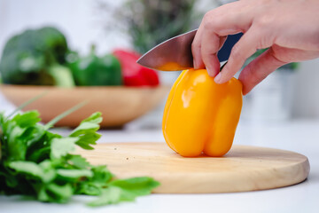 Woman hands cutting bell pepper in the kitchen. Chef cooking vegan food. Chef preparing vegetables in kitchen