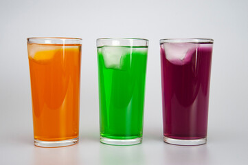 three glasses with different juices with ice on a white background
