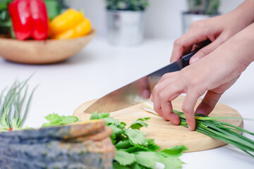 Woman hands cutting scallion in the kitchen. Chef cooking vegan food. Chef preparing vegetables in kitchen