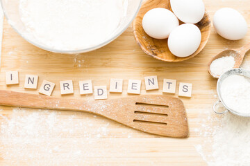 The word ingredients is laid out on the table. on the table is: a bowl of dough, flour, eggs, salt, sugar, strainer. Cooking baking